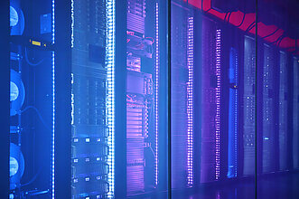 TERRA CLOUD Cube Reihe von Serverracks in einem Rechenzentrum, beleuchtet mit blauem und violettem LED-Licht hinter einer Glaswand